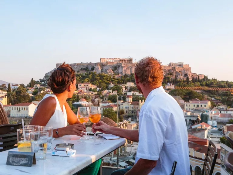 Couple drinking and enjoying the view of the Acropolis at sunset. Athens, Greece