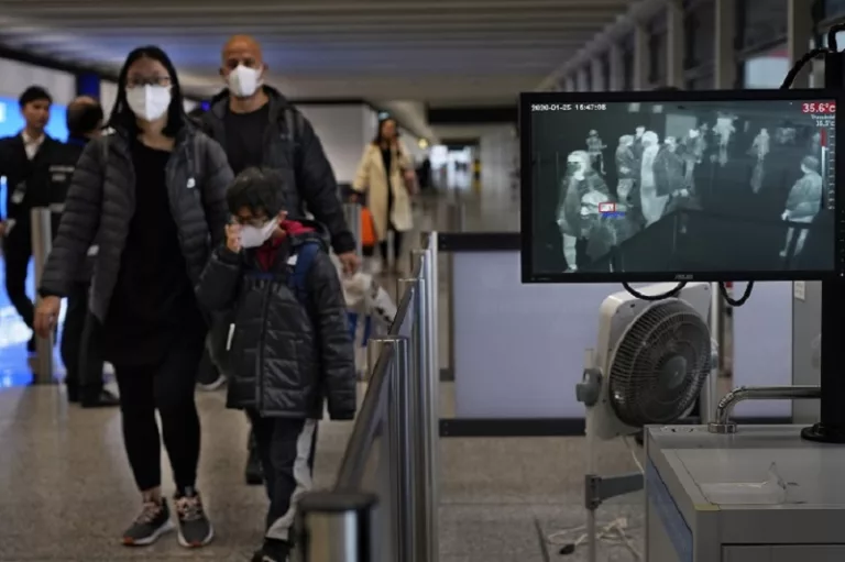 Health surveillance officer use temperature scanner to monitor passengers arriving at Hong Kong International Airport in Hong Kong Saturday, Jan. 25, 2020. Hong Kong has declared the outbreak of a new virus an emergency and will close primary and secondary schools for two more weeks after the Lunar New Year holiday. City leader Carrie Lam also announced Saturday that trains and flights from the city of Wuhan would be blocked. (AP Photo/Vincent Yu)